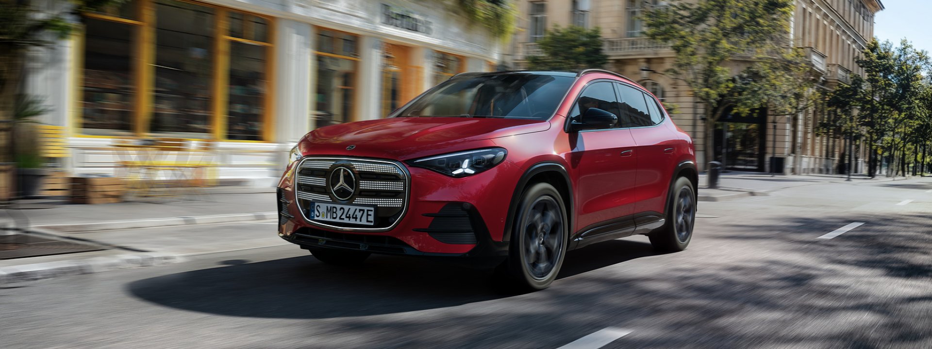 Red Mercedes-Benz electric GLA driving through a city street