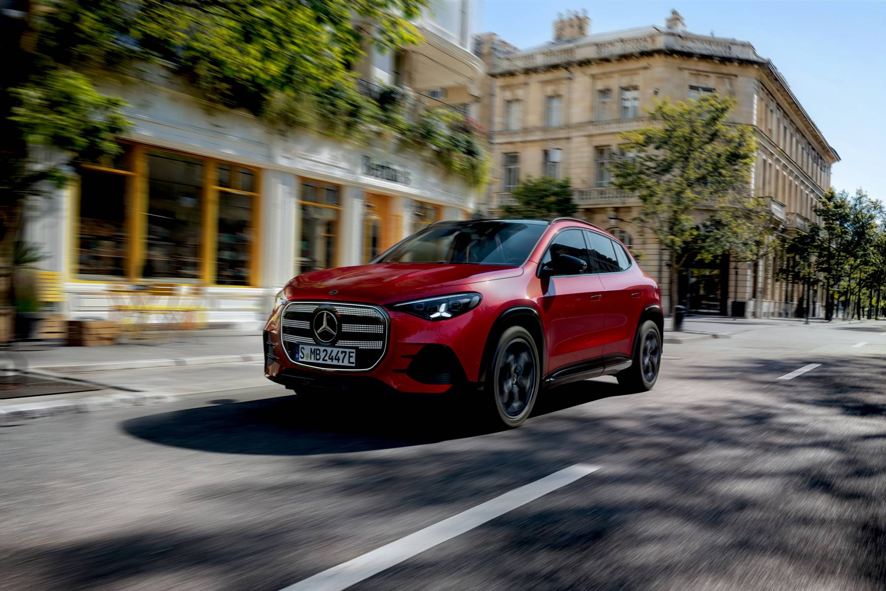 Red Mercedes-Benz electric GLA driving through an urban street